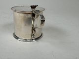 a silver cup with a handle on a white table