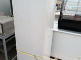 a white refrigerator sitting in a warehouse next to other appliances