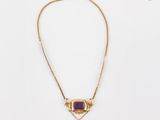 un collier en or orné d'une pierre violette et d'une chaîne en or