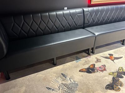 un canapé en cuir noir avec un tapis représentant un papillon posé au sol