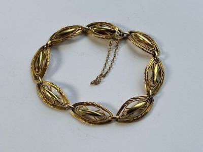 gros plan d'un bracelet en or sur une surface blanche