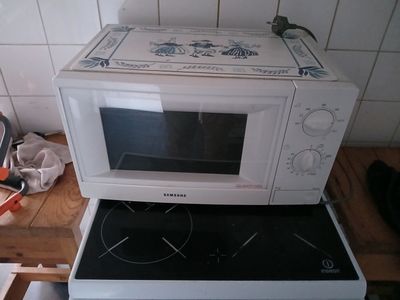 un micro-ondes posé sur une cuisinière dans une cuisine