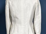 a white jacket on a mannequin stand against a blue wall