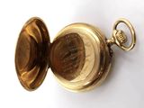 a gold pocket watch with a chain on a white surface