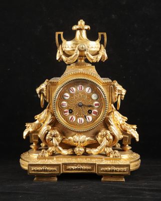 une image représentant une horloge dorée posée sur une surface noire, sur fond noir