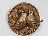 two birds sitting on a tree branch in front of a gold coin