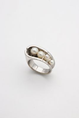 a close up of two peas in a pod ring on a white surface