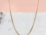 un collier à chaîne en or posé sur une surface en marbre