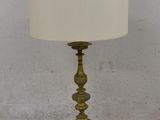 an antique brass table lamp with a white shade on top of it
