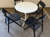 a white table with four black chairs around it