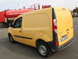 a yellow van parked in a parking lot with a red truck in the background