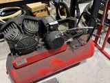 a red air compressor sitting on top of a table