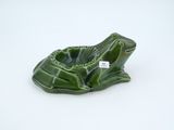 a small green frog shaped ashtray on a white surface