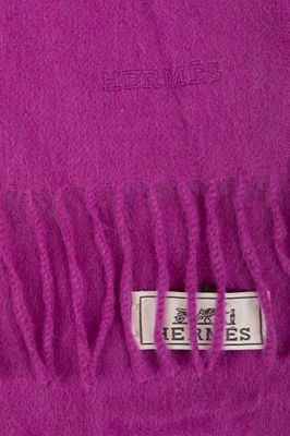 purple wool scarf with fringes on top of it on a white surface