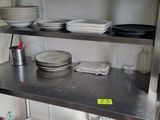 une étagère en métal sur laquelle sont posés des plats, dans une cuisine