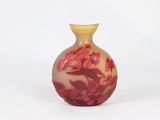 a small vase with red flowers on it on a white surface