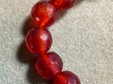 a red beaded bracelet that has a heart charm on it