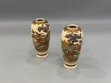 two vases with designs of birds and flowers on them on a table