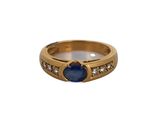 gros plan d'une bague en or avec une pierre bleue et des diamants