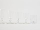 six clear wine glasses lined up in a row on a white surface