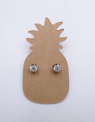 un gros plan d'un ananas sur lequel sont posées une paire de boucles d'oreilles