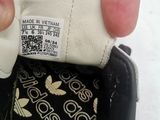 someone is holding a black and white adidas sneaker in their hand