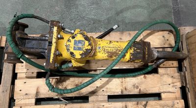 une machine jaune avec un tuyau vert posée sur une palette