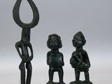 deux figurines noires représentant un homme et une femme tenant une lance
