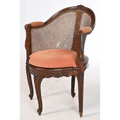 an old fashioned chair with a cane back and orange upholstered seat