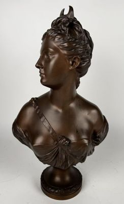 un buste en bronze représentant une femme en robe, posé sur un socle