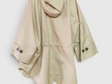 the back view of a beige raincoat hanging on a hanger