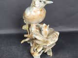statue of a bird sitting on a nest with two baby birds