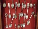 une photo montrant un ensemble de cuillères en argent exposées dans un cadre vitré