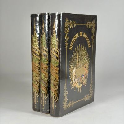 two black books with gold designs on them sitting on a white surface