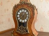 a clock on a shelf in a room with a wallpapered wall