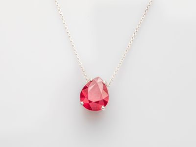 a red heart shaped crystal necklace on a gold chain