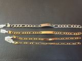 two gold and silver bracelets on a black leather surface