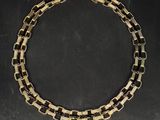 a close up of a gold and black necklace on a black surface