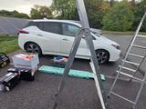 a white car parked in a parking lot next to a ladder