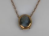 a close up of a necklace with a blue stone on it