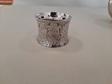 a silver cup sitting on a table next to a vase