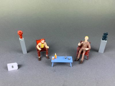 trois figurines représentant des personnes assises sur des chaises les unes à côté des autres