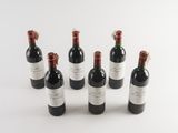 six bottles of wine are lined up on a white surface