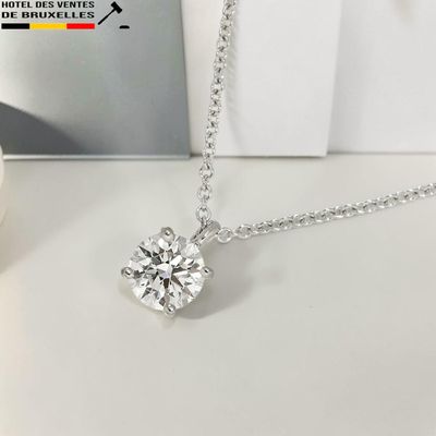un gros plan sur un collier en diamants posé sur une table, à côté d'une tasse de café
