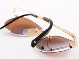 sunglasses on a white surface with a black handle and a gold rim