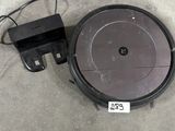 un gros plan d'un robot aspirateur posé sur le sol, avec son chargeur
