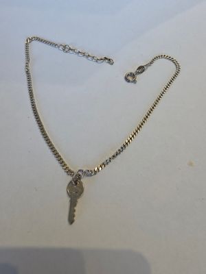 un gros plan d'un collier en argent avec une clé suspendue à une chaîne