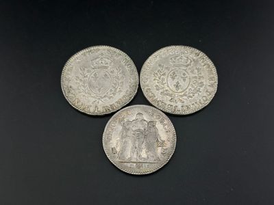 trois pièces d'argent posées les unes à côté des autres sur une surface noire