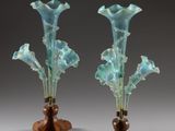 une paire de vases en verre bleu posés sur un socle en bois, sur fond gris