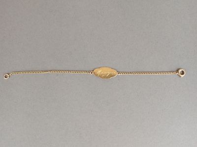 Gros plan sur un bracelet en or orné d'une pièce de monnaie